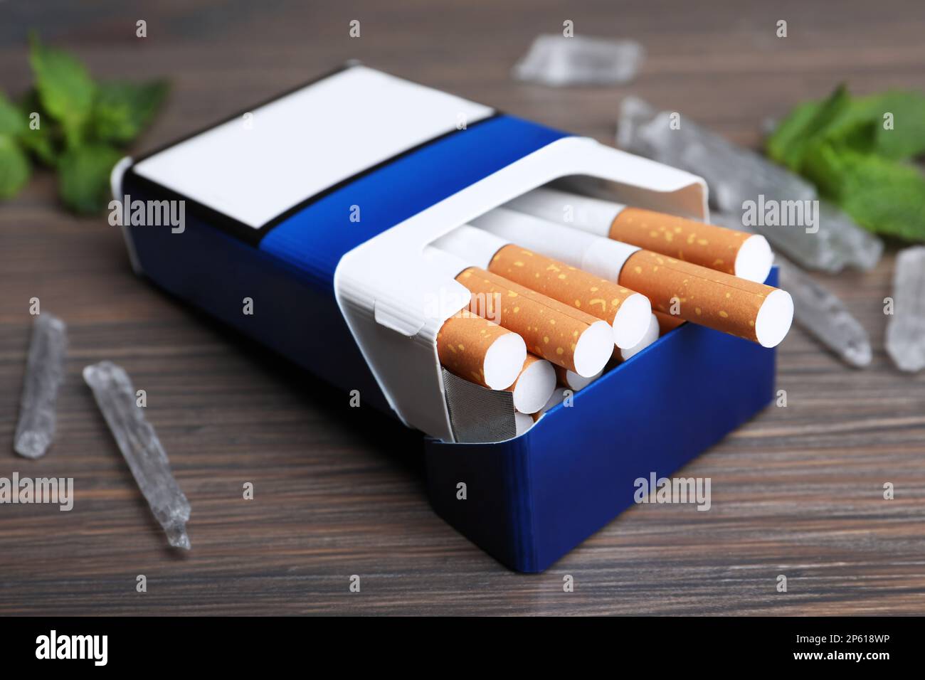 Paquet de cigarettes et de cristaux de menthol sur table en bois, gros plan Banque D'Images