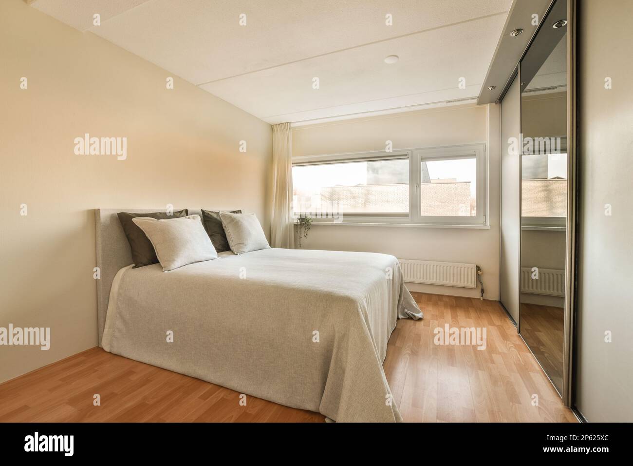 un lit dans une chambre avec parquet et draps blancs sur le cheveu Banque D'Images