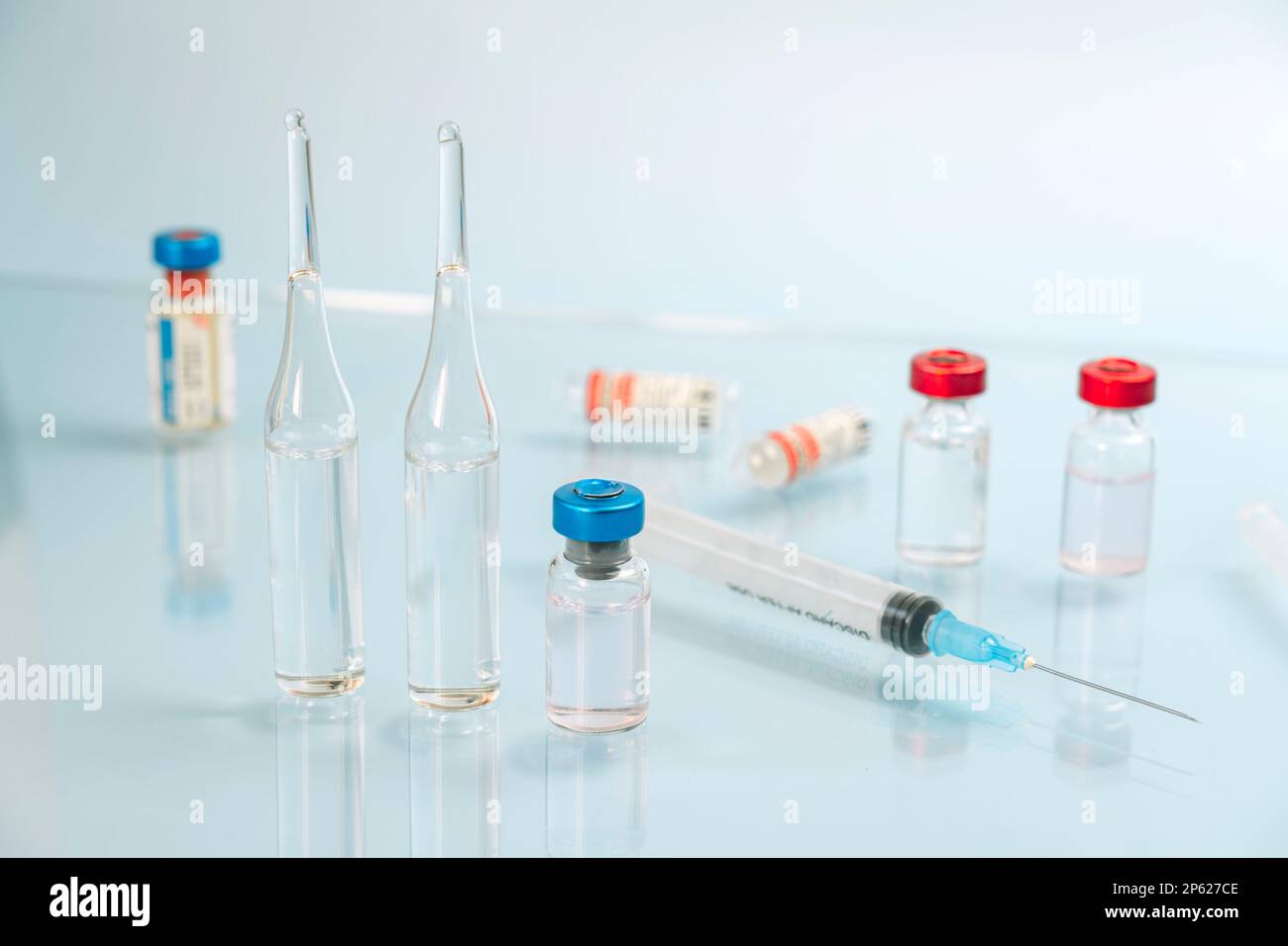 une seringue avec une aiguille et des flacons de liquide sur fond bleu non réfléchissant. Le concept de vaccination et de médecine. immunisation, Banque D'Images