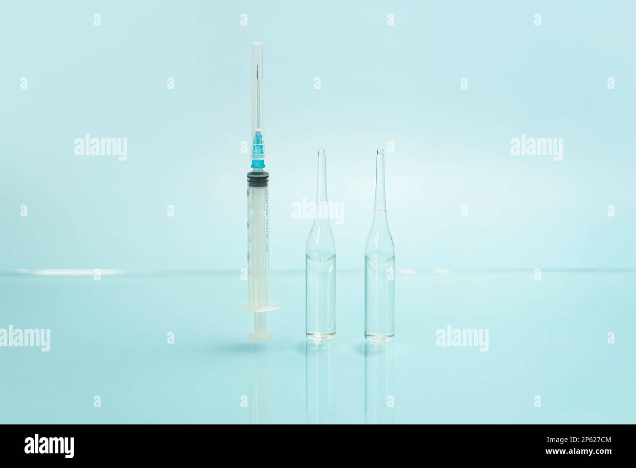 une seringue et des flacons en verre avec un liquide transparent sur fond bleu. le concept de médecine et de santé. Banque D'Images
