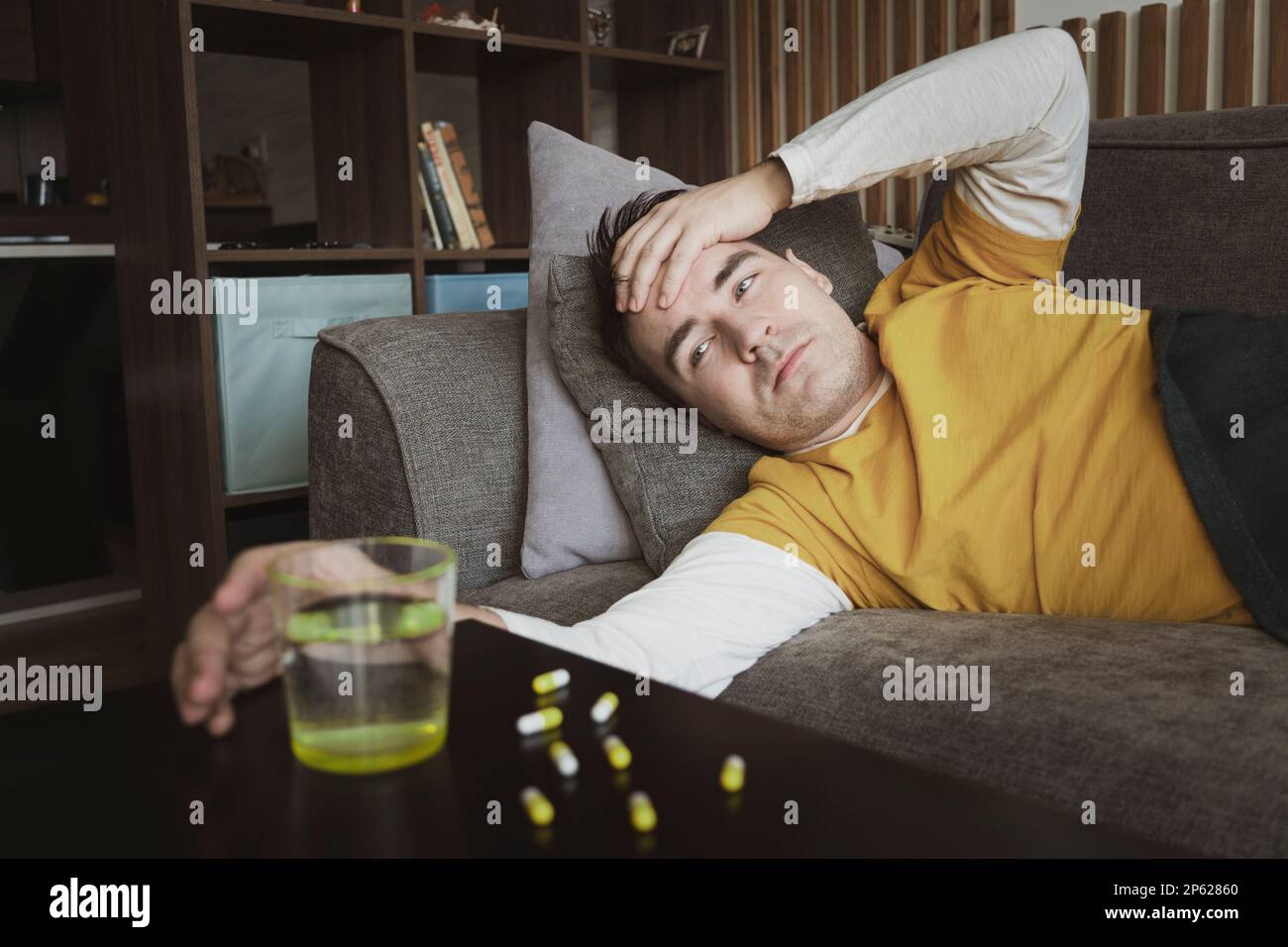 le jeune homme prend des médicaments, la bouche ouverte et apporte des médicaments à la bouche. automédication. guy est traité à la maison avec des pilules Banque D'Images