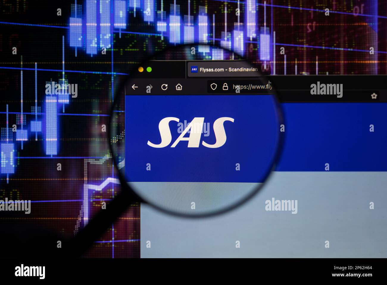 Le logo de la compagnie aérienne SAS sur un site Web avec des développements flous du marché boursier en arrière-plan, vu sur un écran d'ordinateur à travers une loupe Banque D'Images