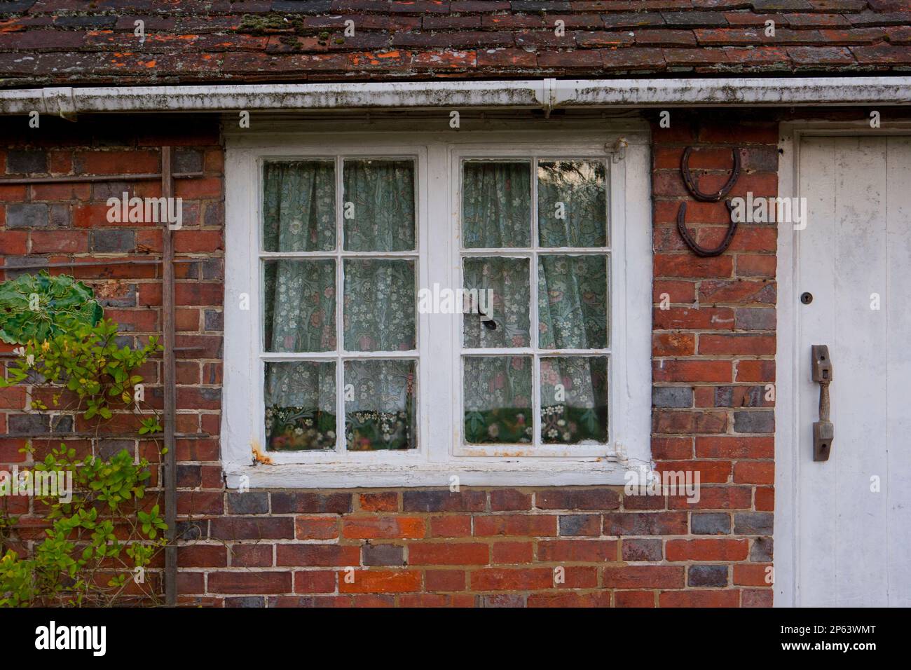 Ancienne maison de campagne en briques blanches fenêtres avec rideaux fleuris Banque D'Images