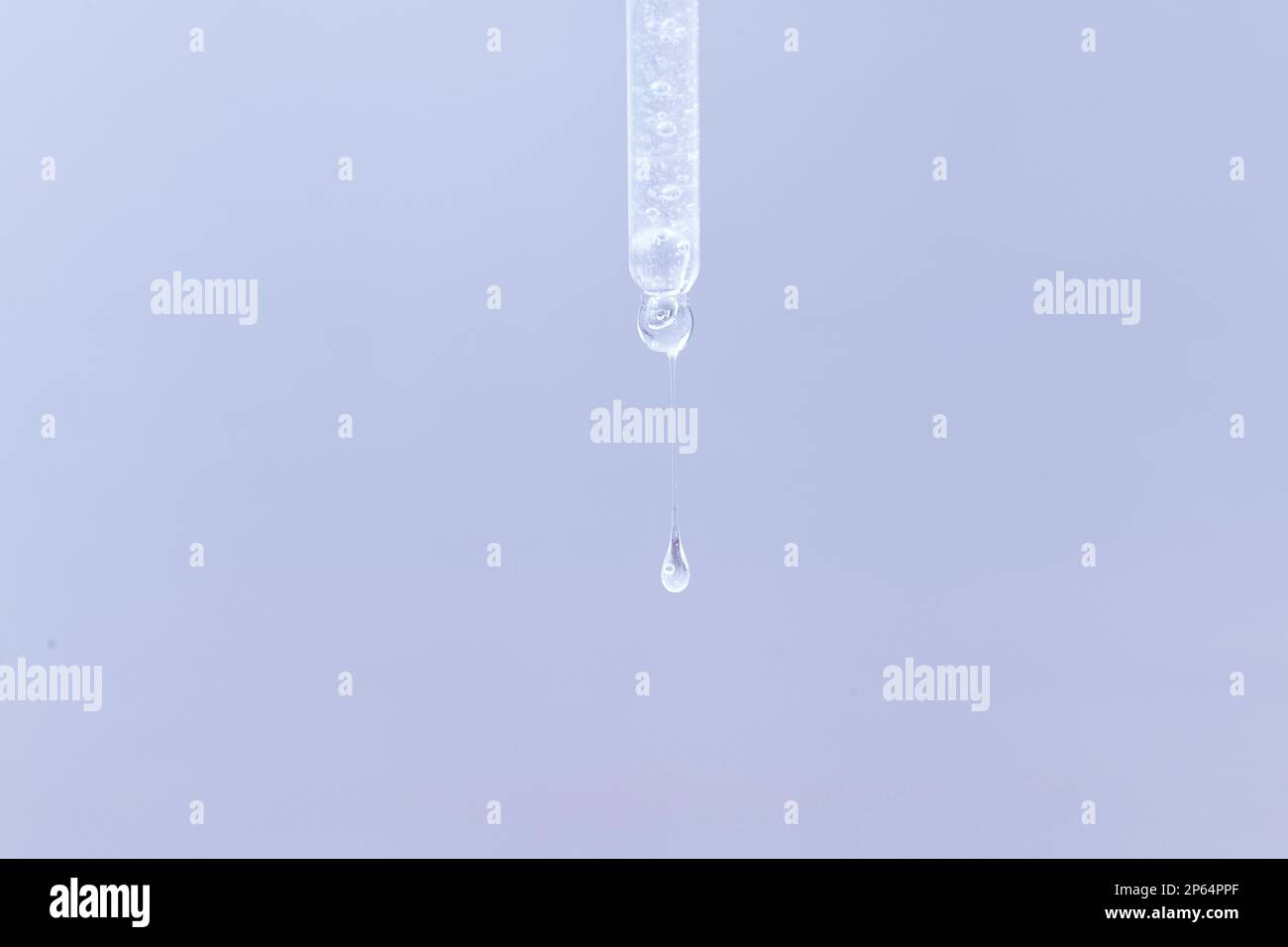 Pipette cosmétique avec une goutte transparente de sérum gros plan sur fond bleu Banque D'Images