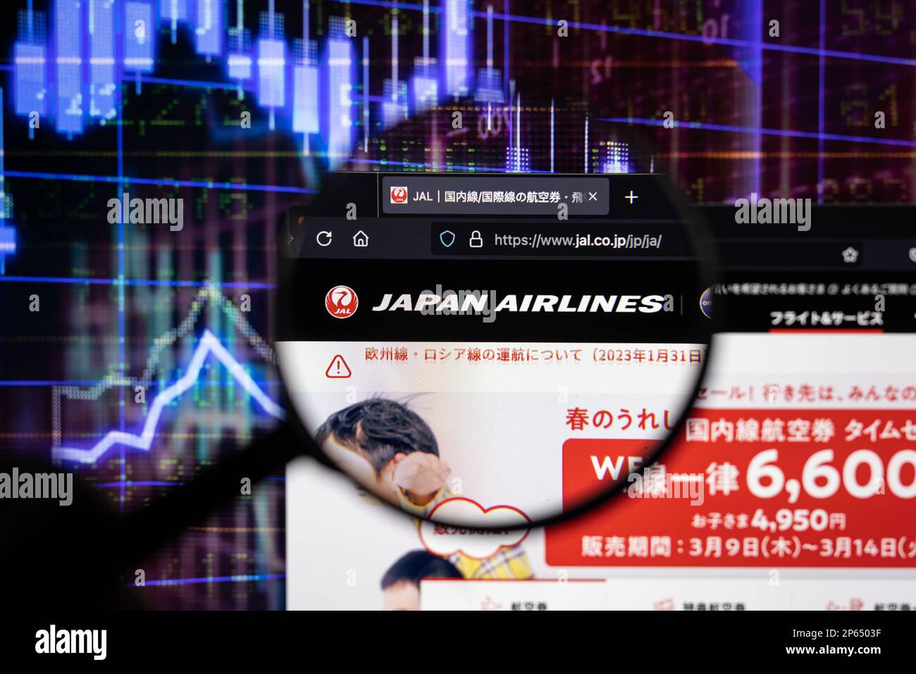 Logo de la société Japan Airlines sur un site Web présentant des développements flous sur le marché boursier en arrière-plan, vu sur un écran d'ordinateur à travers une loupe Banque D'Images