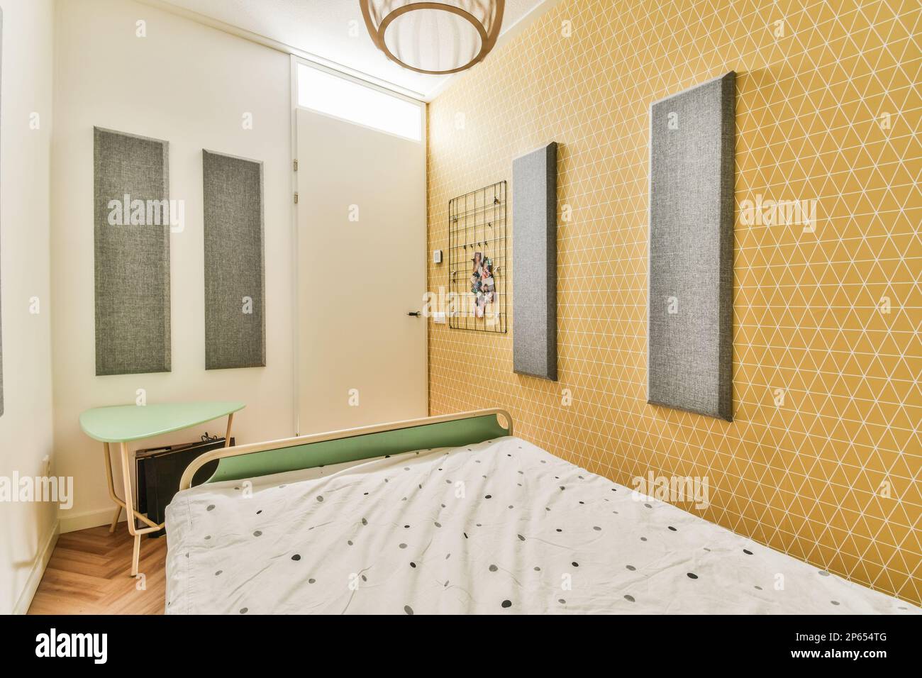 Amsterdam, pays-Bas - 10 avril 2021 : une chambre avec papier peint jaune et des feuilles blanches sur le lit devant deux photos accrochées au mur Banque D'Images