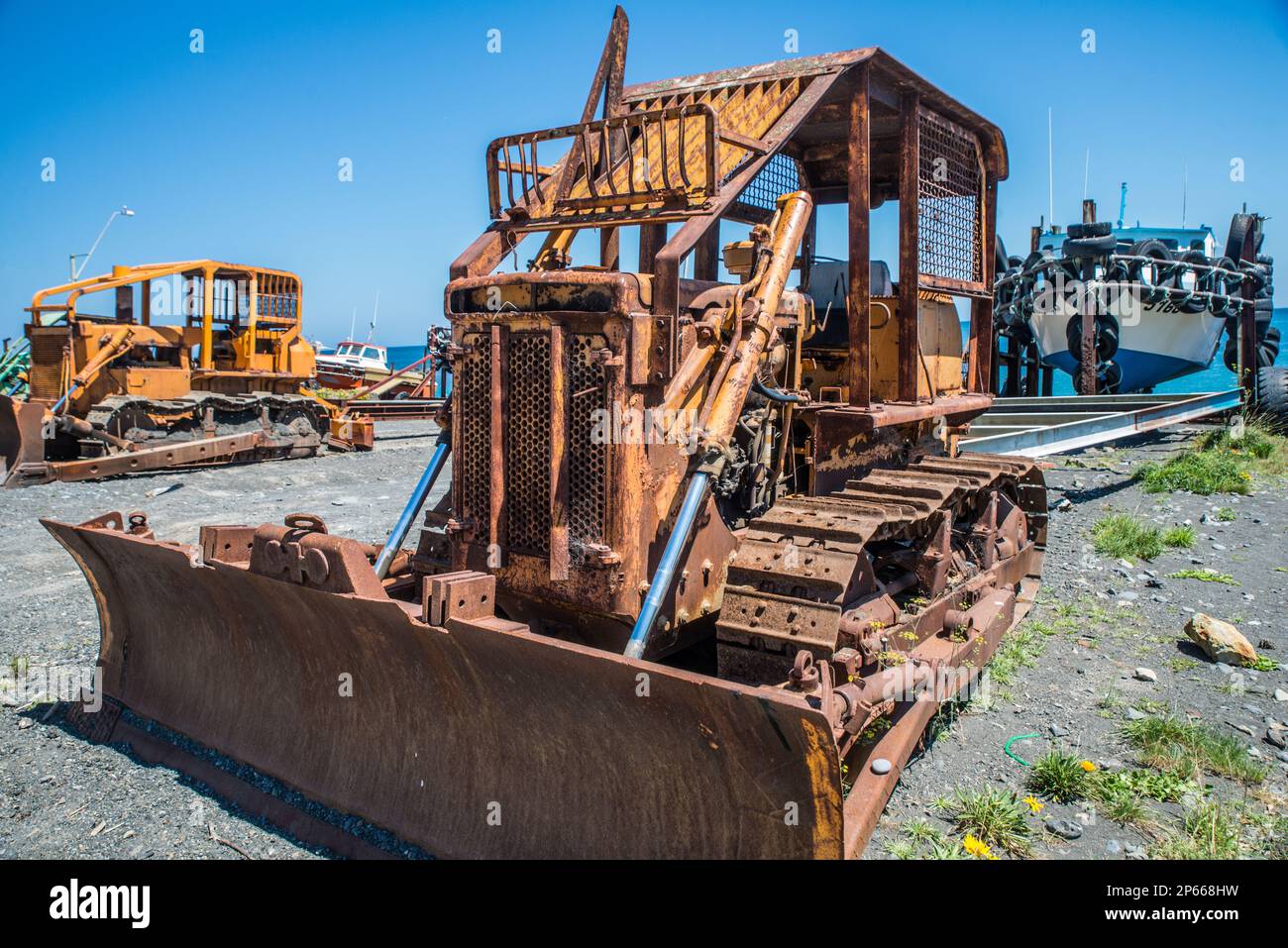 Un vieux bulldozer rouillé sur une plage de sable noir utilisé pour lancer des bateaux en Nouvelle-Zélande Banque D'Images