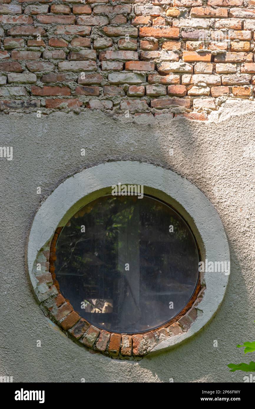 Une fenêtre ronde dans un vieux bâtiment en ruines. Banque D'Images