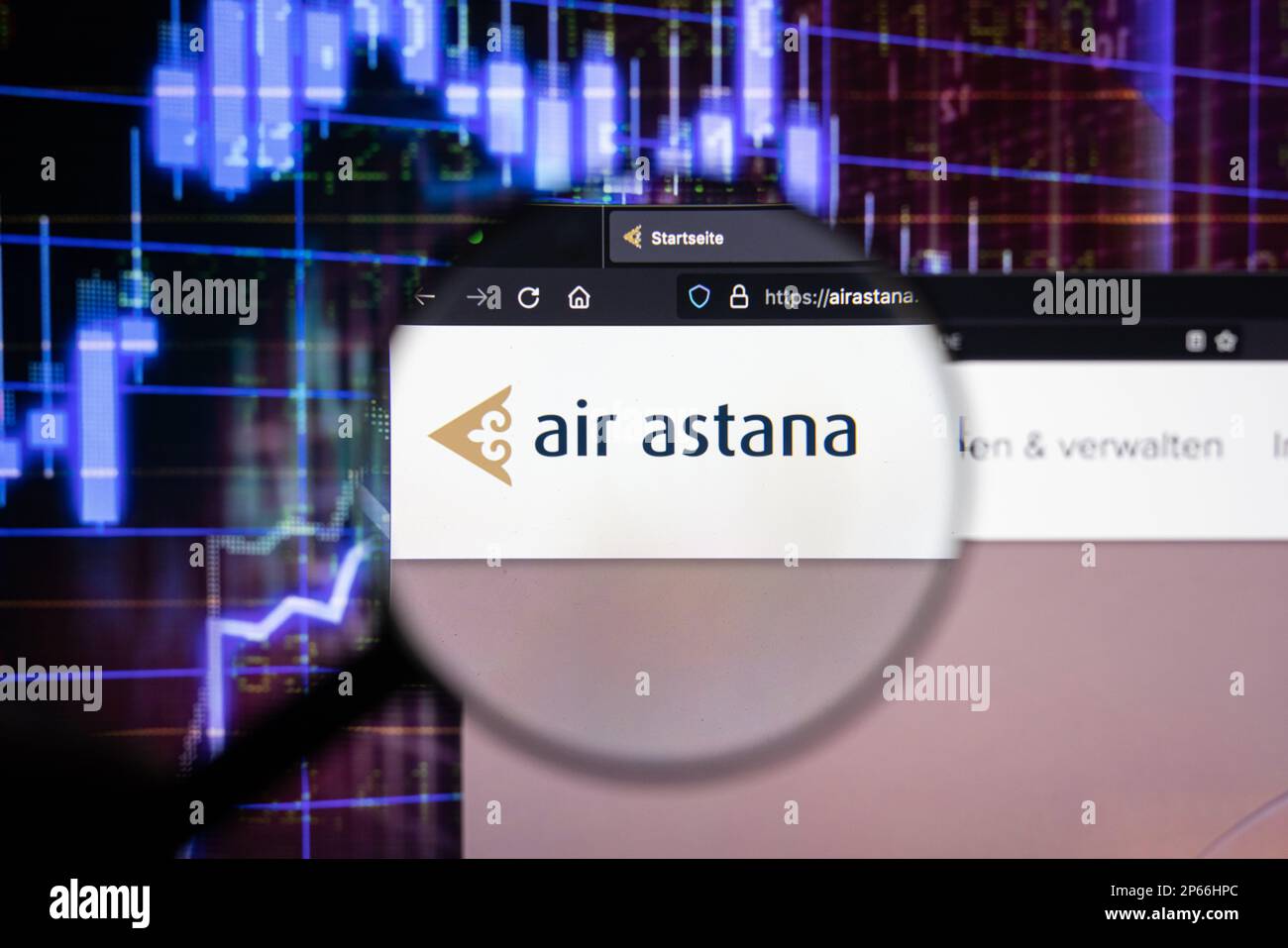 Le logo de la compagnie aérienne Air Astana sur un site Web avec des développements flous du marché boursier en arrière-plan, vu sur un écran à travers une loupe Banque D'Images