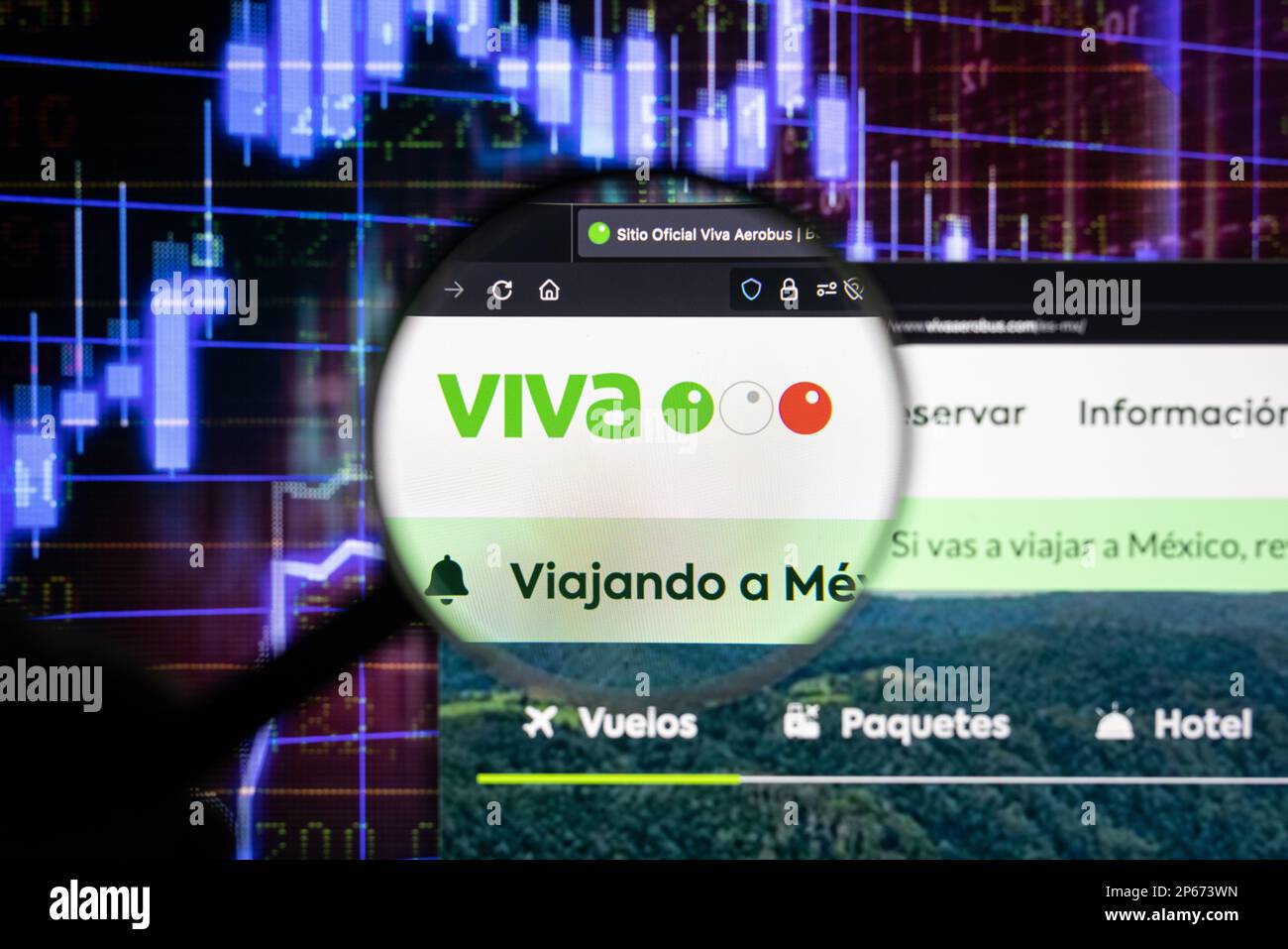 Le logo de la compagnie aérienne Viva sur un site Web avec des développements flous de marché boursier en arrière-plan, vu sur un écran d'ordinateur à travers une loupe Banque D'Images