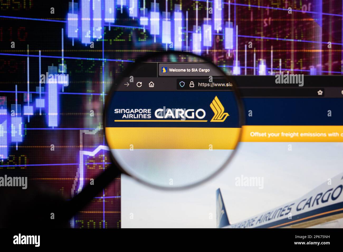 Logo de la compagnie de fret de Singapore Airlines sur un site Web avec des développements flous du marché boursier en arrière-plan, sur un écran à travers une loupe Banque D'Images