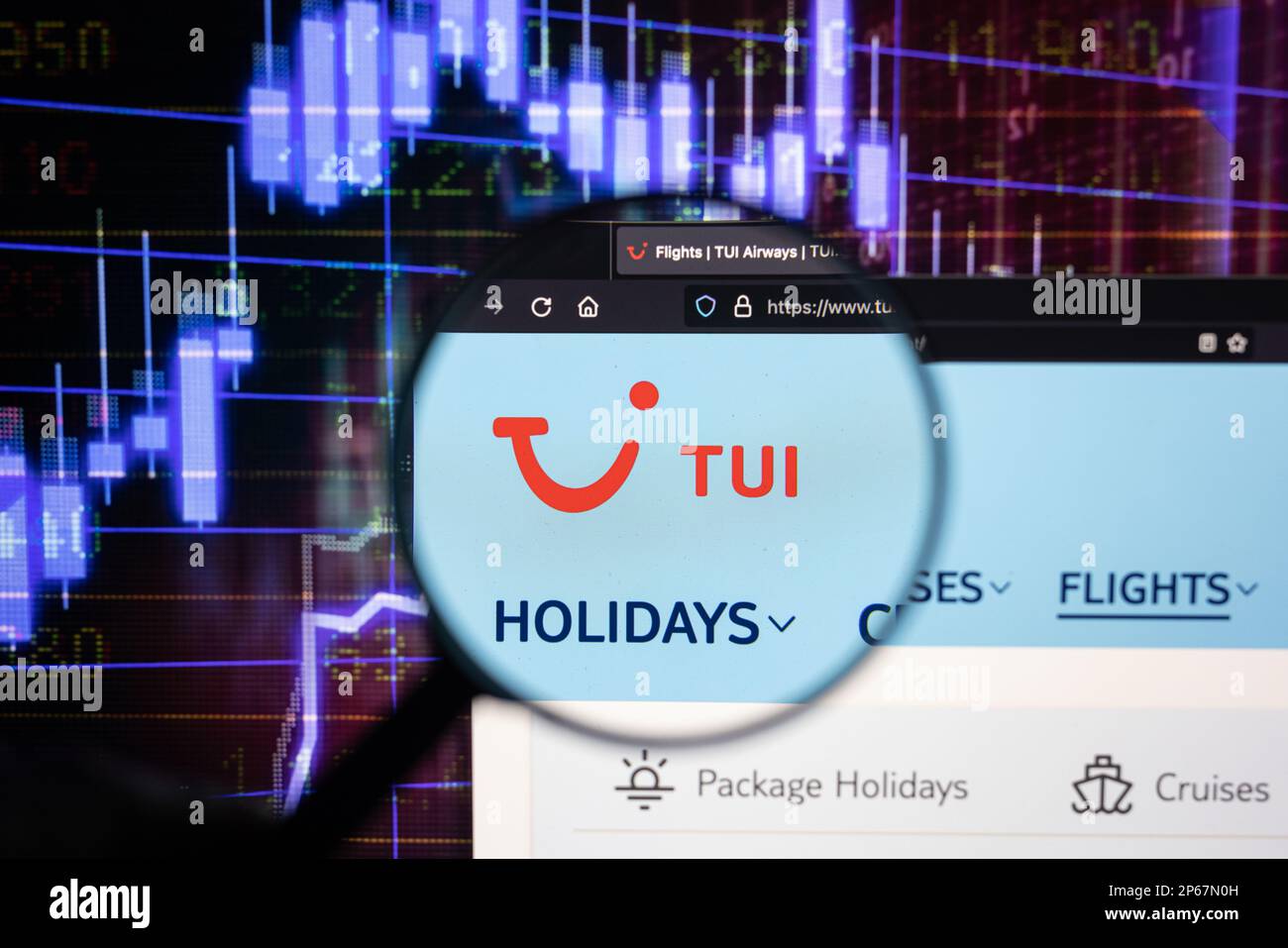 Le logo de la compagnie aérienne TUI sur un site Web avec des développements flous du marché boursier en arrière-plan, vu sur un écran d'ordinateur à travers une loupe Banque D'Images