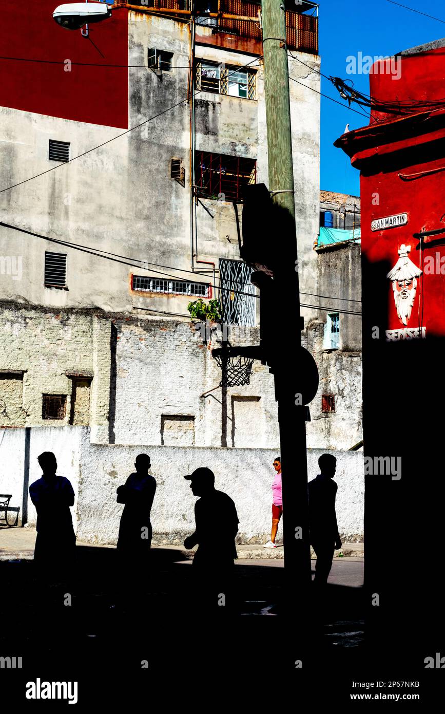 Silhoueted figures contre des bâtiments aux couleurs vives, filet de basket-ball au coin de la rue, San Martin, Old Havana, Cuba, West Indies, Caraïbes Banque D'Images