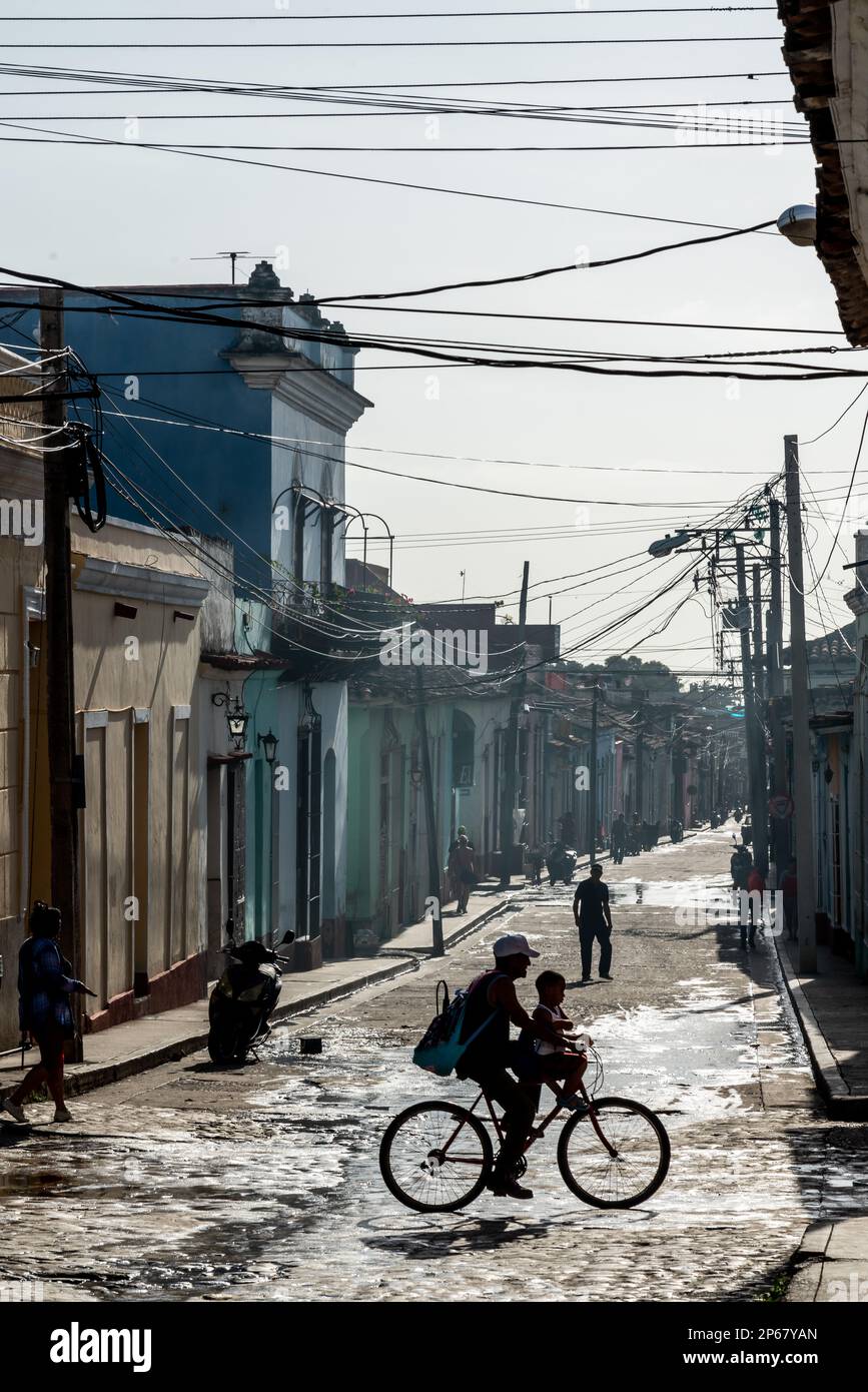 Arrière-rue typique sous une panoplie de fils téléphoniques, famille silhoueté sur le vélo, Trinidad, Cuba, Antilles, Caraïbes, Amérique centrale Banque D'Images