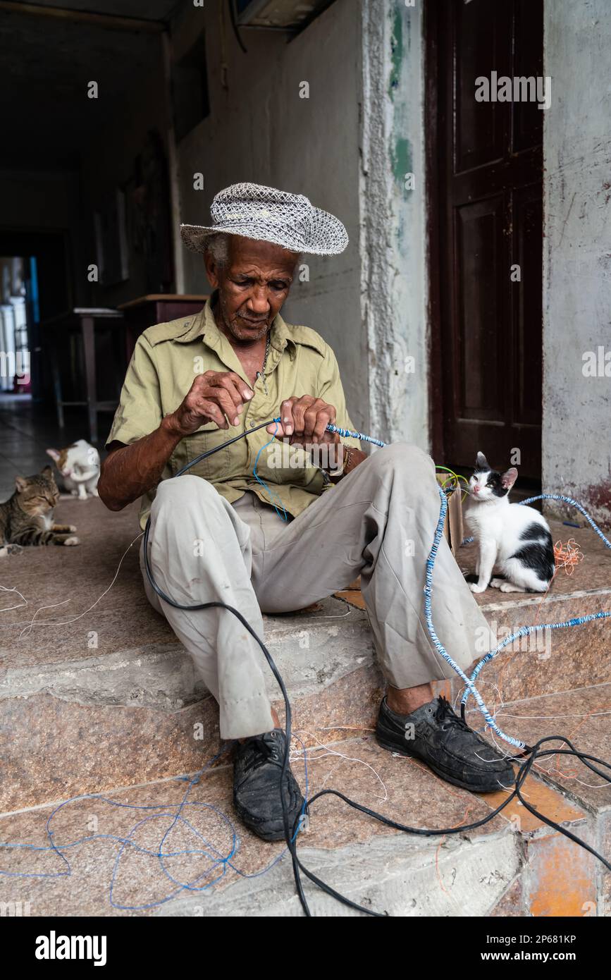 Électricien se câblant en nœuds avec ses chats, Santa Clara, Cuba, Antilles, Caraïbes, Amérique centrale Banque D'Images