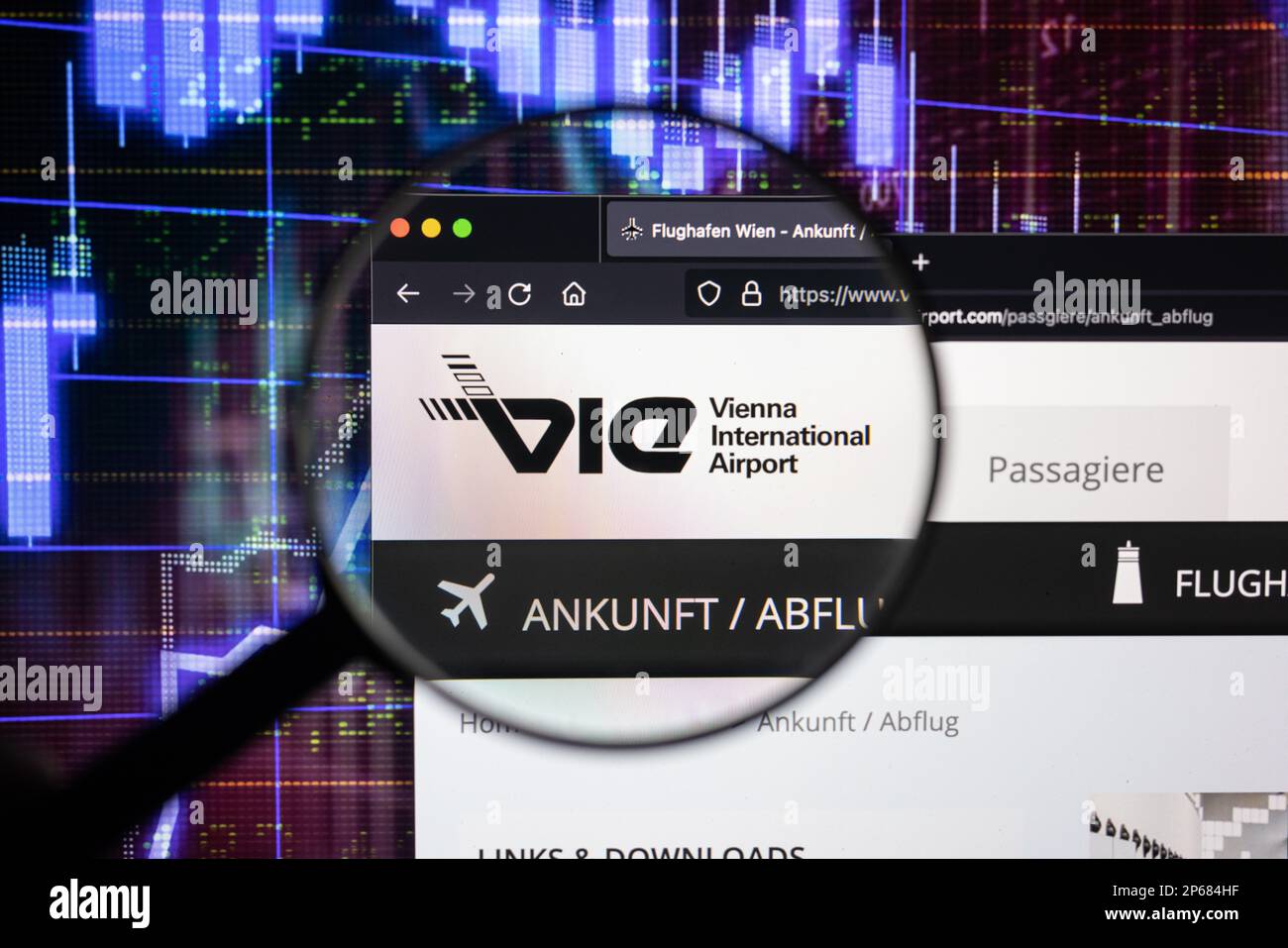 Le logo de la compagnie de l'aéroport de Vienne sur un site Web avec des développements flous du marché boursier en arrière-plan, vu sur un écran d'ordinateur à travers une loupe Banque D'Images