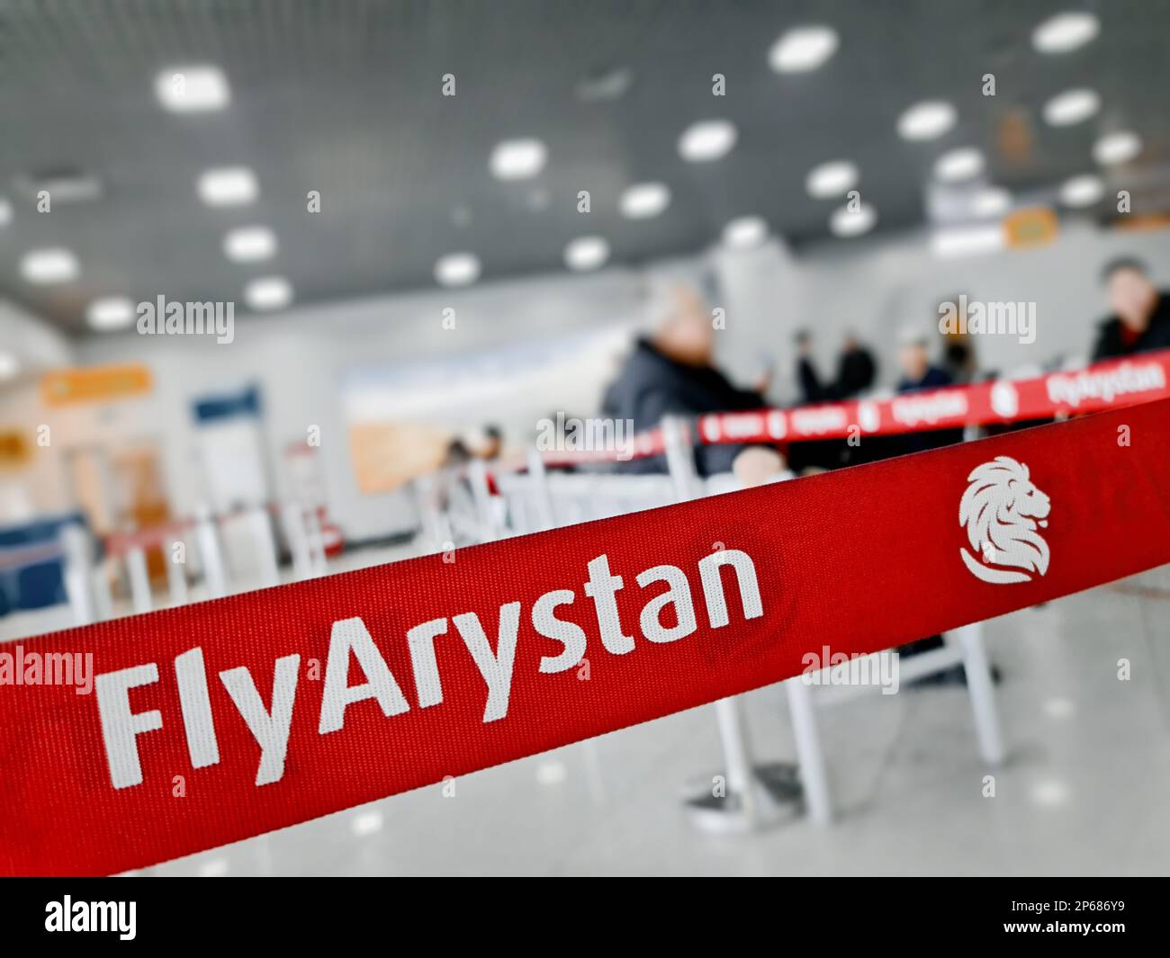 Ruban barrière avec le logo Fly Arystan dans la salle d'attente avec des visiteurs à l'aéroport international Banque D'Images