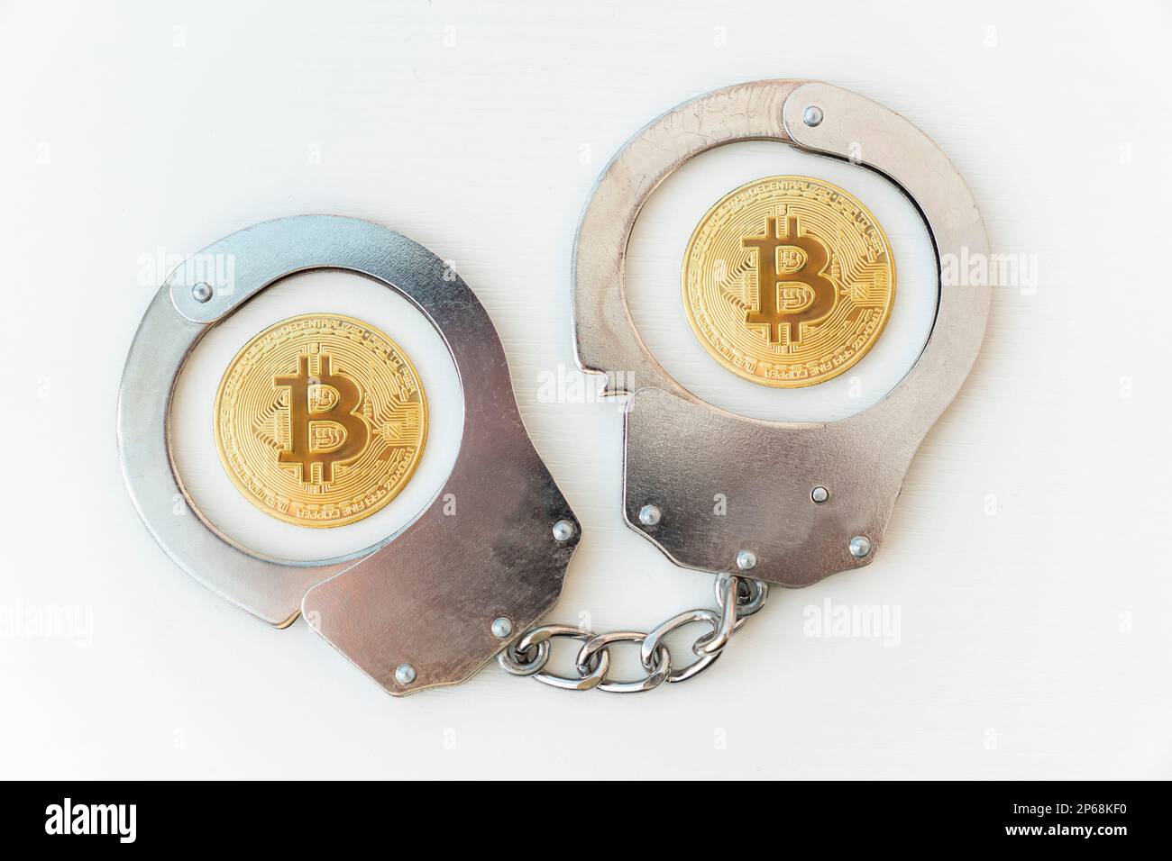 prison pour utilisation des paiements en crypto-monnaie. Menottes et bitcoin doré sur une table blanche. Banque D'Images