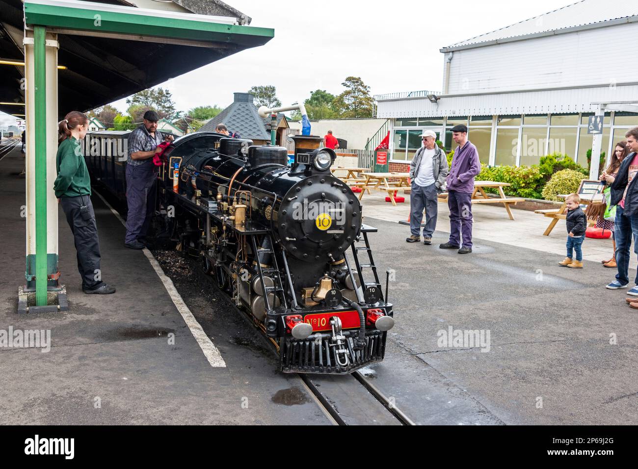 Un chauffeur de moteur donne un dernier nettoyage avant que la petite locomotive à vapeur ne quitte la gare de New Romney pour un voyage sur Romney, Hythe & Dymchu Banque D'Images