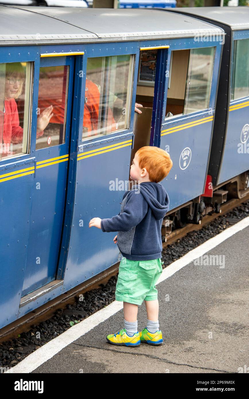 Un jeune garçon à côté d'une petite calèche à la gare de New Romney pour une promenade sur le train à vapeur miniature Romney, Hythe & Dymchurch (RH&DR) Banque D'Images