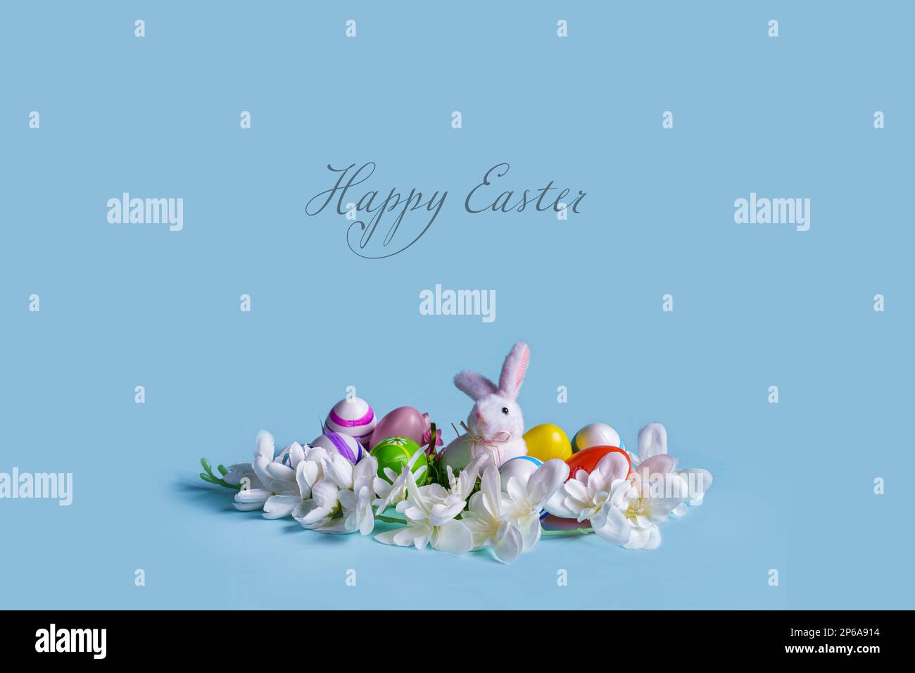 La carte de Pâques présente un design minimaliste avec un fond bleu pastel et une décoration faite de fleurs, d'œufs décorés et d'un joli lapin. Le centre Banque D'Images