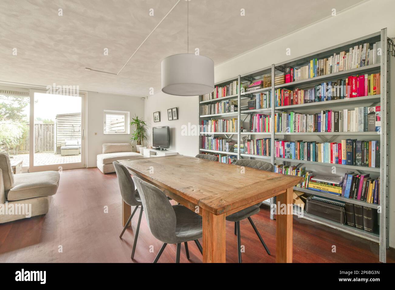Amsterdam, pays-Bas - 10 avril 2021 : un salon avec de nombreux livres sur les étagères et une table en bois dans la salle est bien éclairé par la lumière du soleil Banque D'Images
