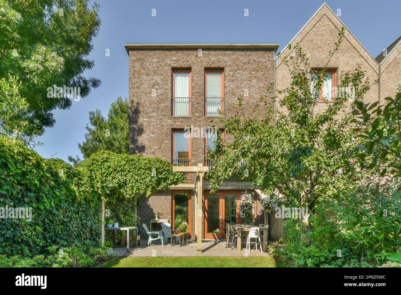 l'extérieur d'une maison avec quelques arbres et des buissons devant elle sur un ciel bleu clair jour ou jour ensoleillé Banque D'Images