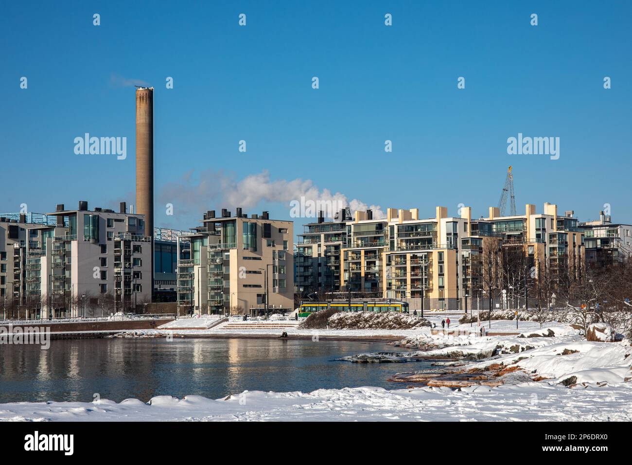 La plage d'Eiran ranta ou d'Eiranranta a été enneigée avec des bâtiments résidentiels modernes d'Hernesaari en arrière-plan, lors d'une journée d'hiver ensoleillée à Helsinki, en Finlande Banque D'Images