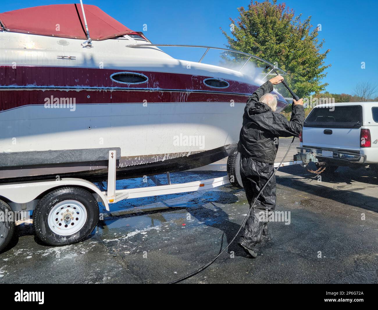 Homme caucasien lavant un bateau à moteur sur une remorque Banque D'Images