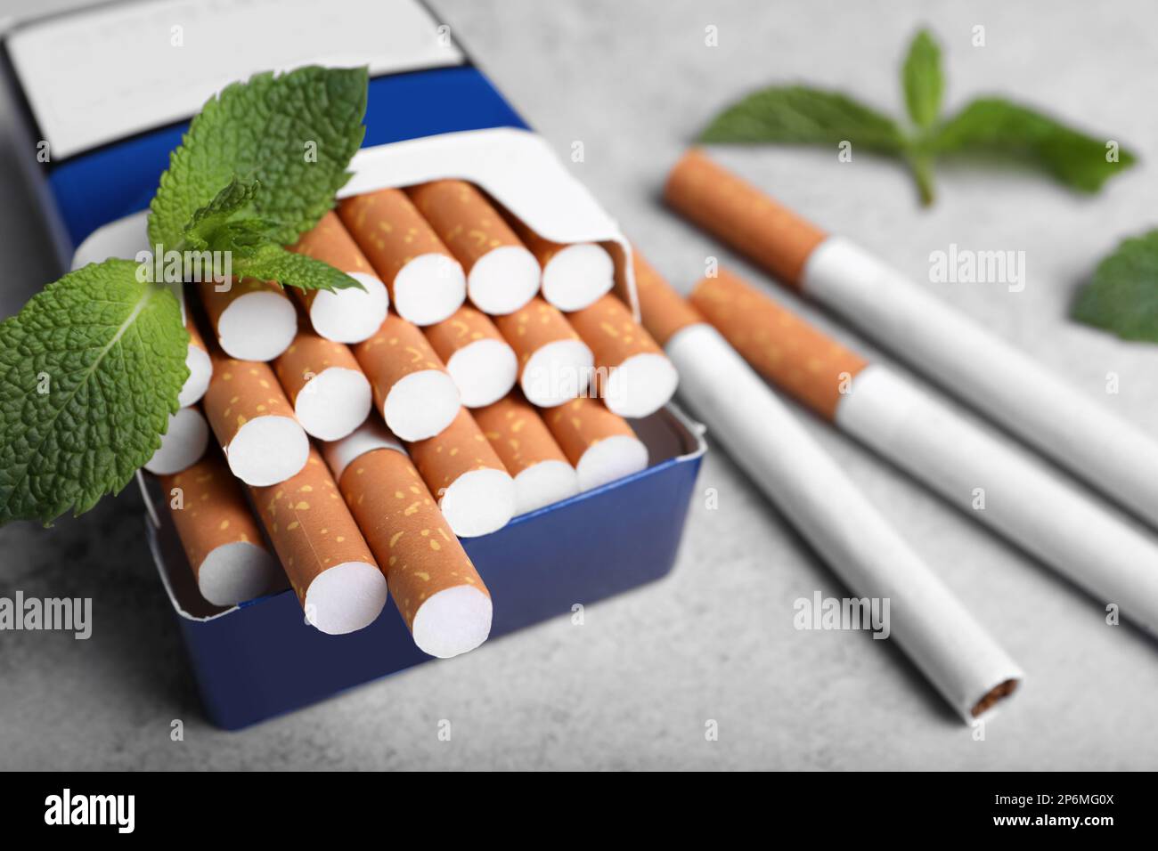 Paquet de cigarettes de menthol et de feuilles de menthe sur table grise, gros plan Banque D'Images