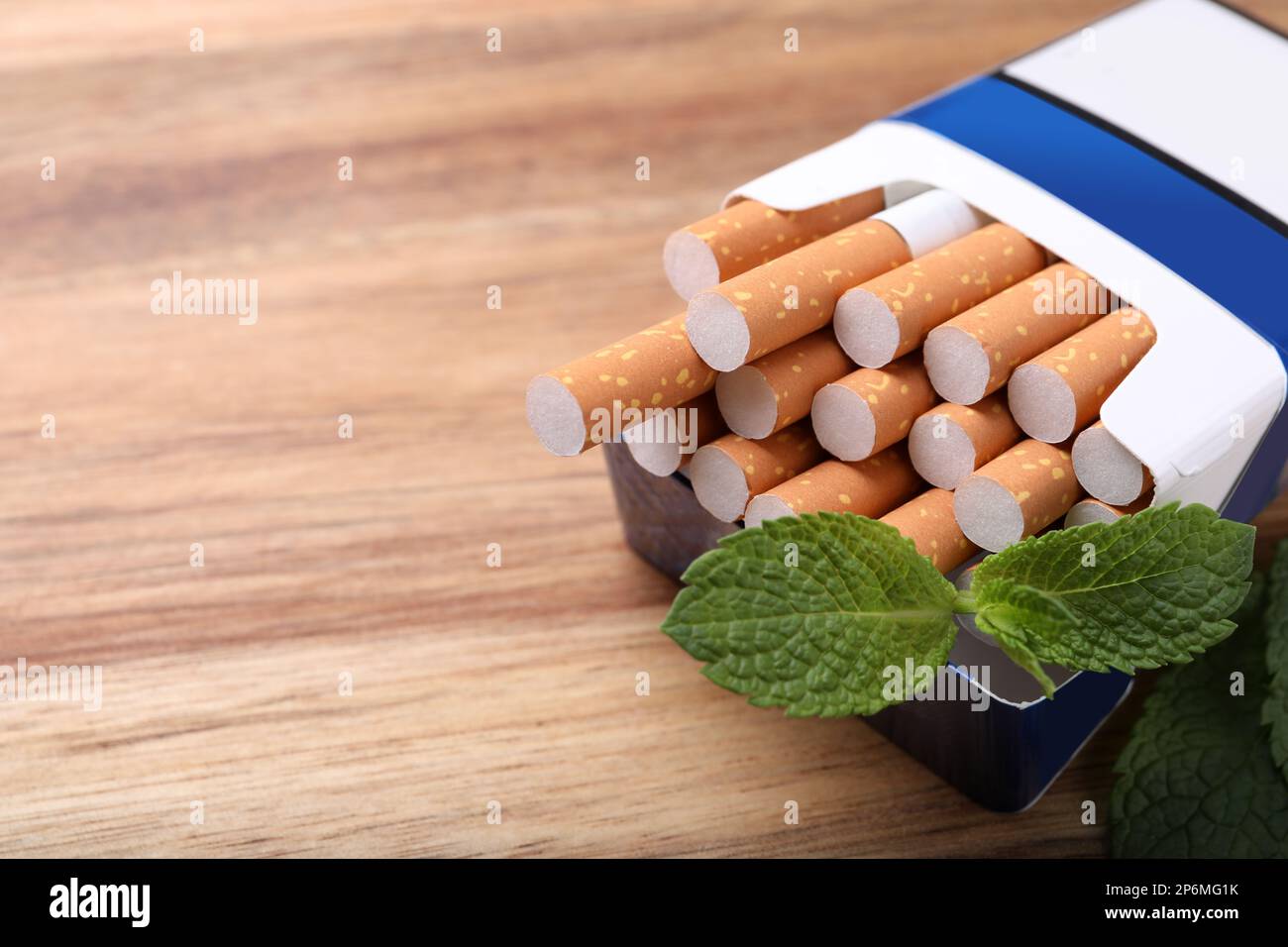 Paquet de cigarettes de menthol et de feuilles de menthe sur table en bois, gros plan. Espace pour le texte Banque D'Images