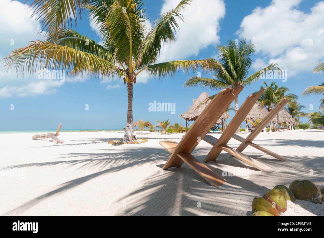 Chaises rustiques sur la plage de sable blanc dans les tropiques avec des palmiers contre le ciel bleu. Holbox Island, Mexique. Concept de voyage de vacances Banque D'Images