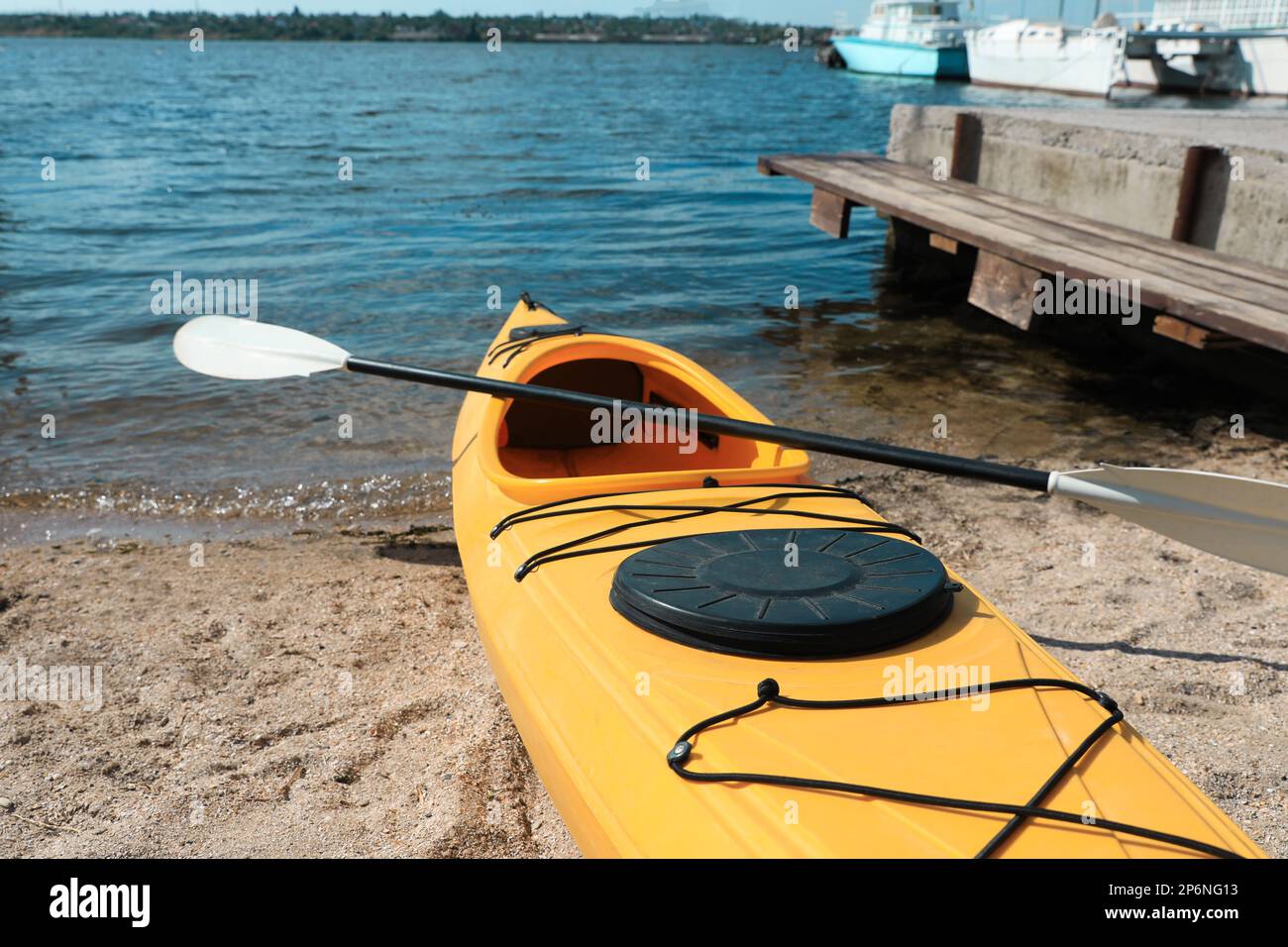 Kayak jaune avec paddle sur la plage près de la rivière. Activité de camp d'été Banque D'Images Kayak jaune avec paddle sur la plage près de la rivière. Activité de camp d'été Banque D'Images