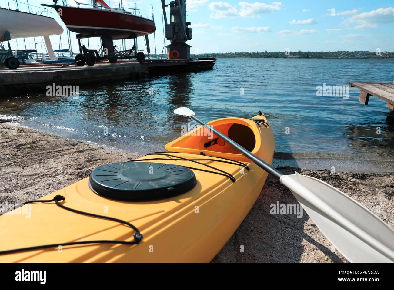 Kayak jaune avec paddle sur la plage près de la rivière, à proximité. Activité de camp d'été Banque D'Images Kayak jaune avec paddle sur la plage près de la rivière, à proximité. Activité de camp d'été Banque D'Images