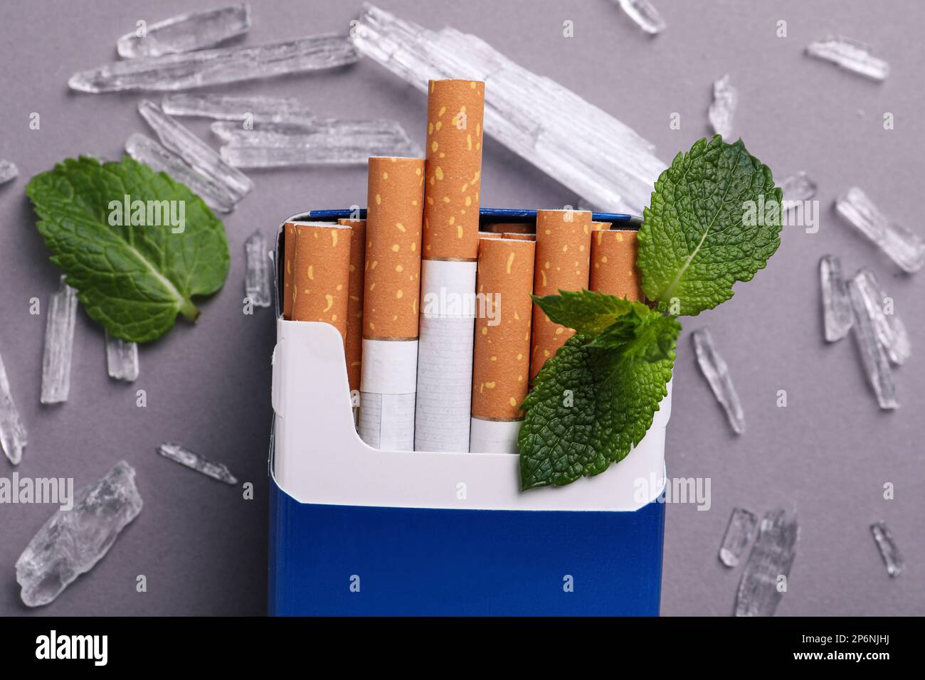 Paquet de cigarettes, de cristaux de menthol et de feuilles de menthe sur fond gris, plat Banque D'Images