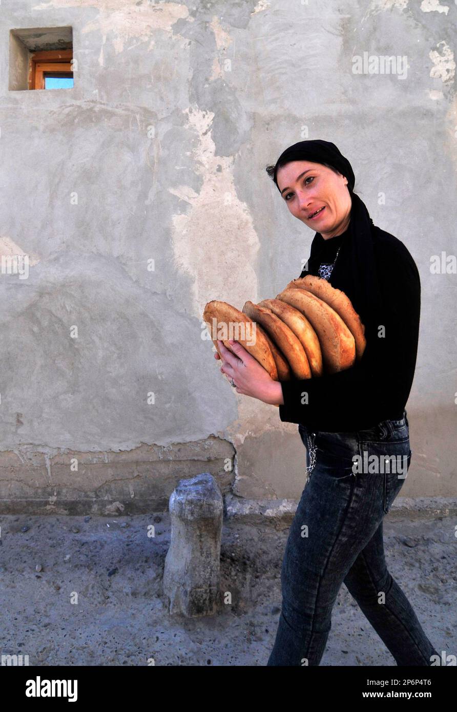 Une femme ouzbek portant du pain local. OBI non- est un pain ouzbek / tadjik traditionnel vendu sur les marchés dans tout l'Ouzbékistan. Banque D'Images