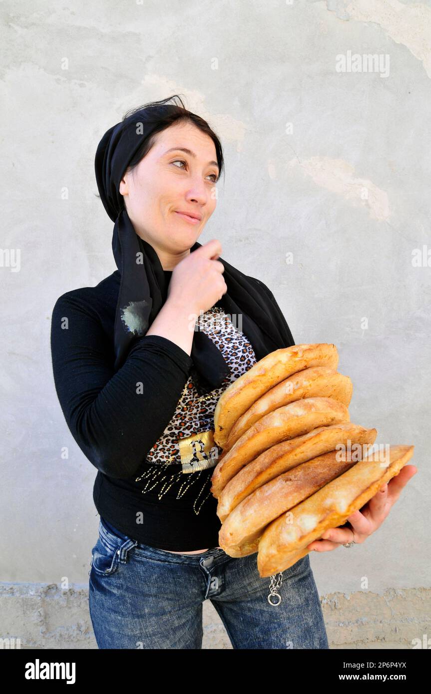 Une femme ouzbek portant du pain local. OBI non- est un pain ouzbek / tadjik traditionnel vendu sur les marchés dans tout l'Ouzbékistan. Banque D'Images