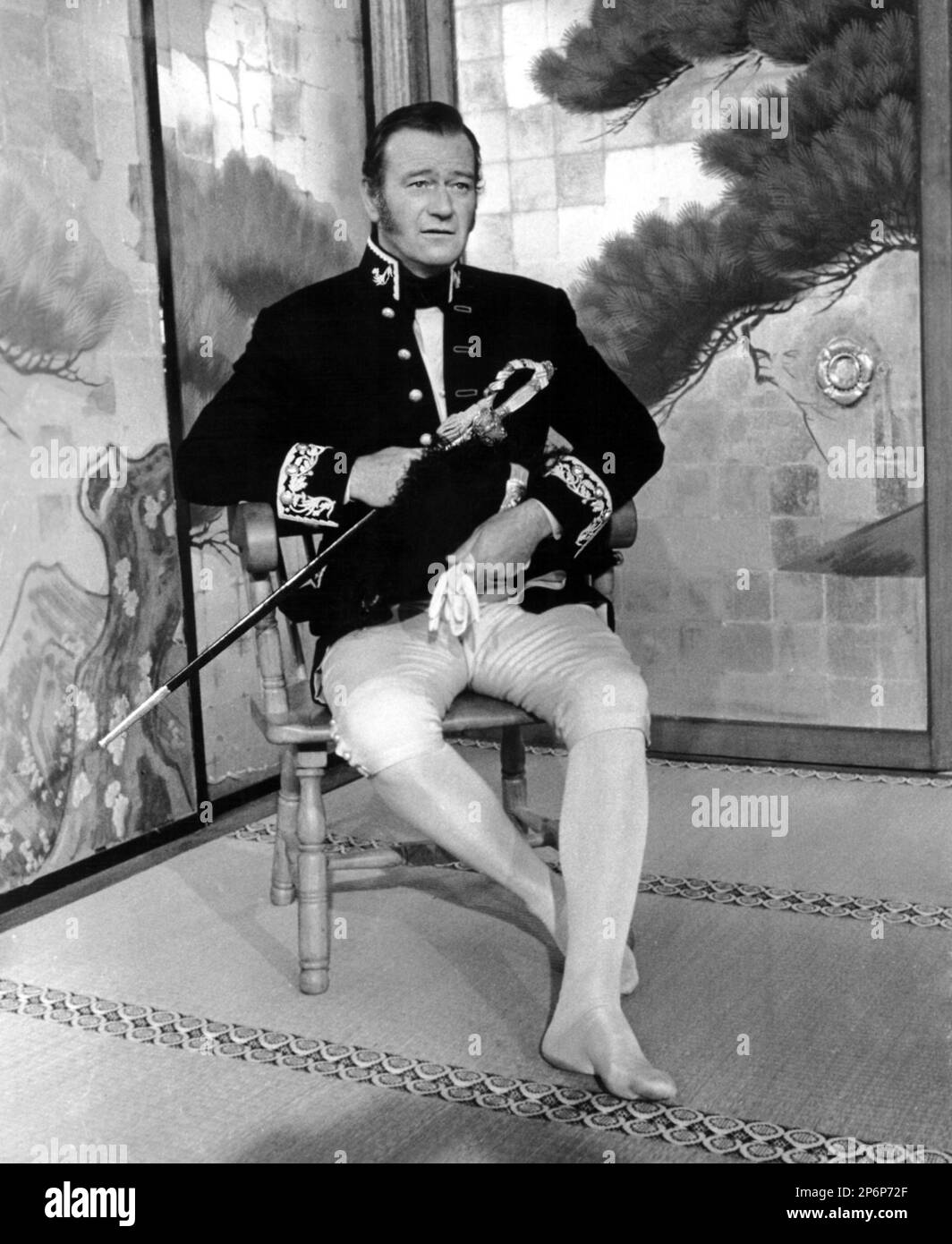 1958: Le célèbre acteur de cinéma JOHN WAYNE dans un cliché pubblicavitaire pour LE BARBARE ET LA GEISHA ( il barbaro e la geisha ) par John Huston , d'un roman d'Ellis St. Joseph - CINÉMA - ATTORE CINEMATOGRAFICO - FILM - spada - épée - piédi scalzi - pieds nus --- Archivio GBB Banque D'Images