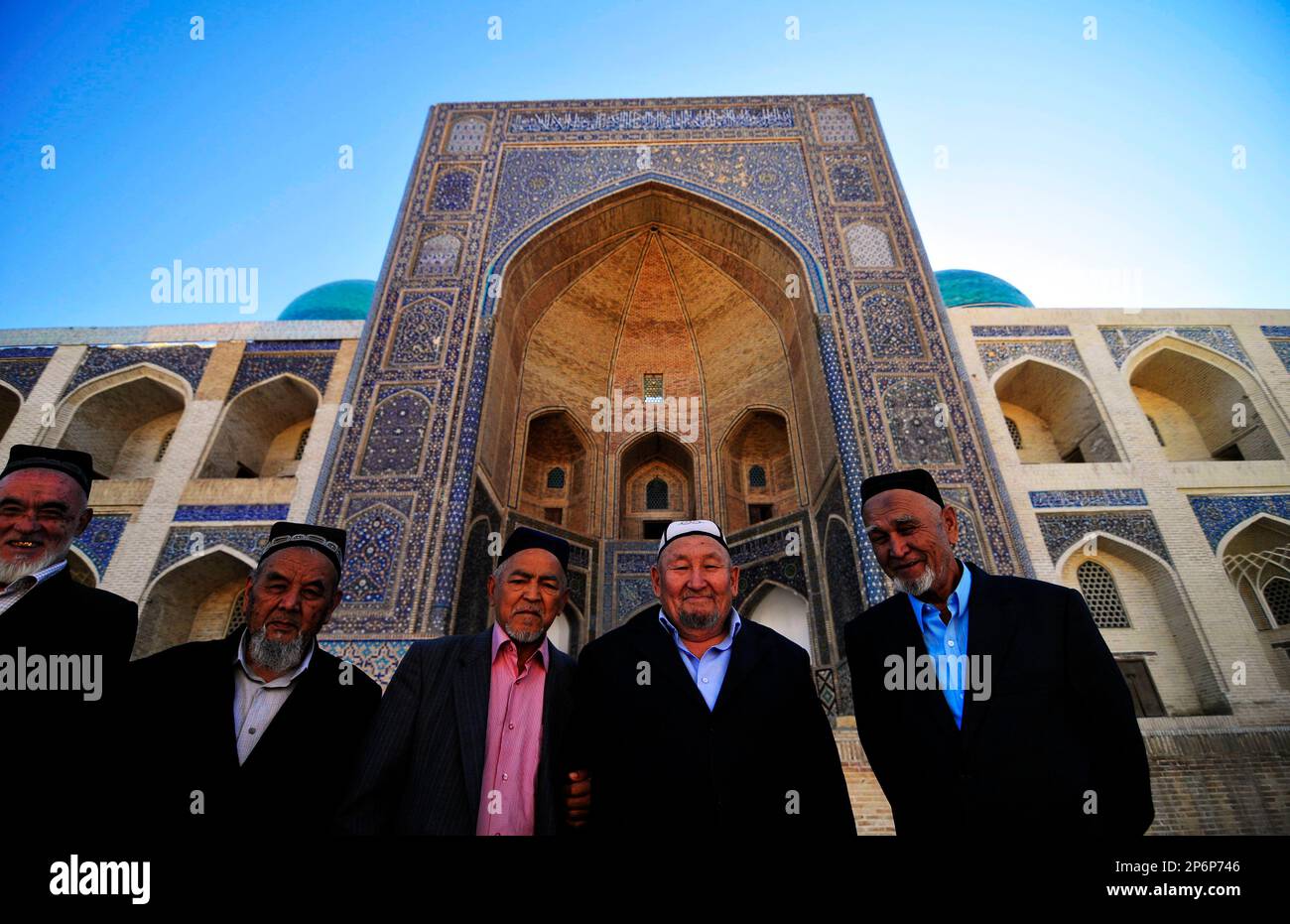 Des hommes ouzbèkes se tenant devant la mosquée de Kalan et la cour dans la vieille ville de Boukhara, Ouzbékistan. Banque D'Images