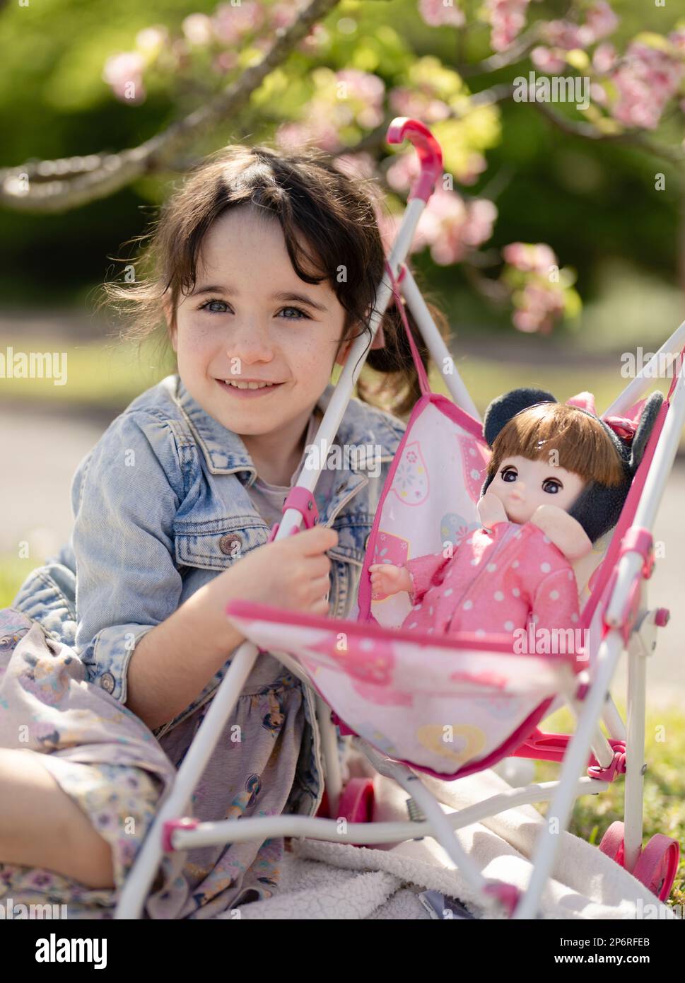 une fille de 5 ans joue avec ses poupées dans une poussette - mimycing parental Banque D'Images
