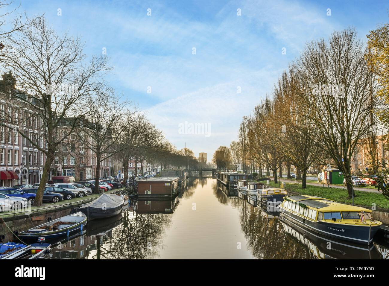 Amsterdam, pays-Bas - 10 avril 2021 : quelques bateaux dans l'eau et des bâtiments des deux côtés, avec des arbres reflétés dans l'eau aussi bien pour eux Banque D'Images