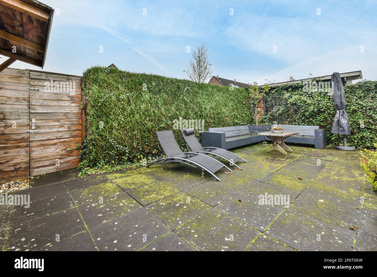 Amsterdam, pays-Bas - 10 avril, 2021: Une cour avec quelques chaises et des plantes sur le sol devant un mur de jardin clôturé en bois Banque D'Images
