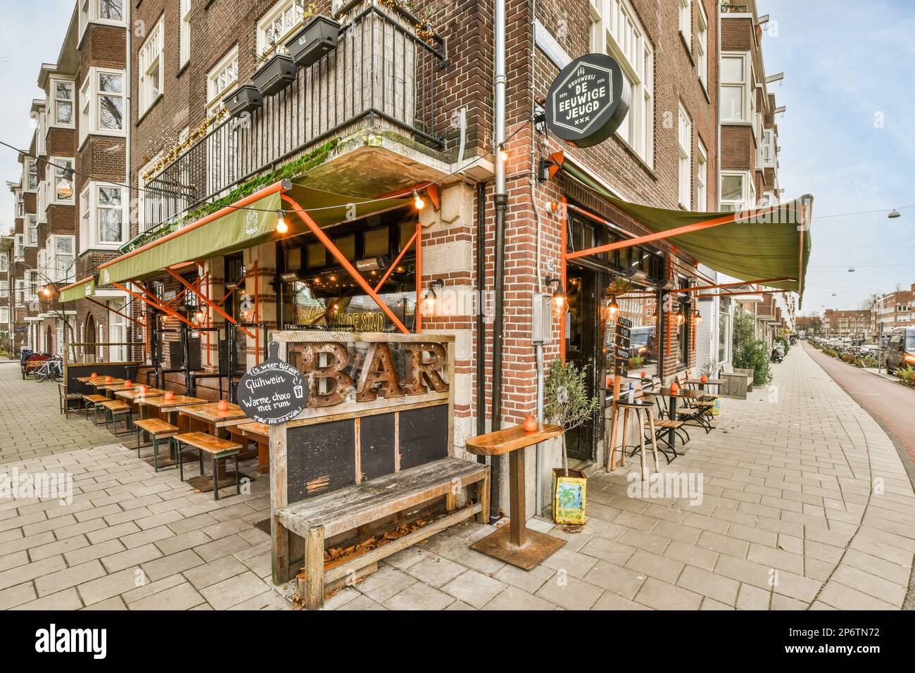 Amsterdam, pays-Bas - 10 avril 2021 : l'extérieur d'un restaurant avec des tables et des bancs sur le trottoir devant un vieux bâtiment en briques qui est utilisé comme un Banque D'Images