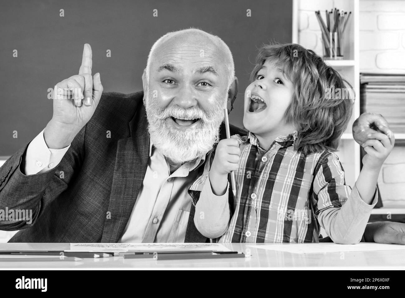 Élève et enseignant en classe. Grand-père et fils s'amusent ensemble. Homme mature enseignant et élève sur fond de babillard. Banque D'Images