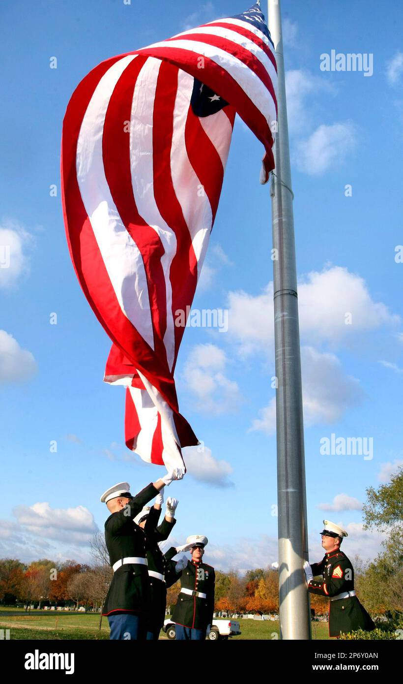 U.S. Marines from the local USMC recruiting station, unfurl a large 15 foot by 25 foot American flag during a Veterans Day Ceremony in the Daniel Morgan Veterans Cemetery in Mount Hebron Cemetery in Winchester, Va. Friday Nov. 11, 2011. (AP Photo/The Winchester Star, Ginger Perry) Banque D'Images
