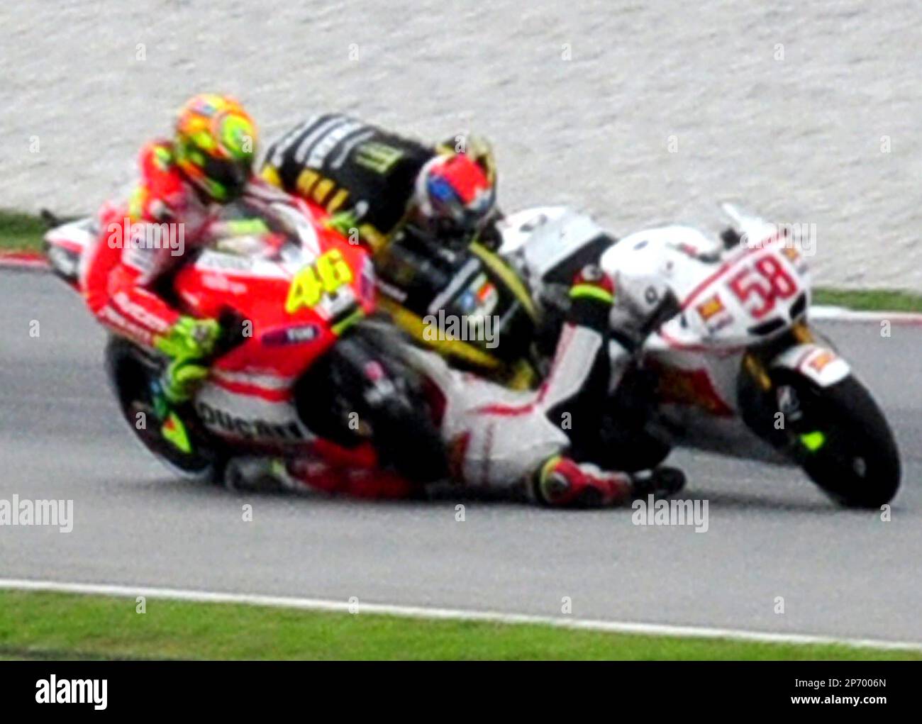 Crash between Colin Edwards, center, Valentino Rossi from Italy, left, and Marco Simoncelli from Italy is seen at turn 11 during the Malaysian MotoGP Grand Prix in Sepang, Malaysia, Sunday, Oct. 23, 2011. Italian rider Simoncelli died of chest, head and neck injuries Sunday after a crash at the Malaysian MotoGP motorcycle race, organizers said. He was 24. (AP Photo/Ruben Yap) Banque D'Images