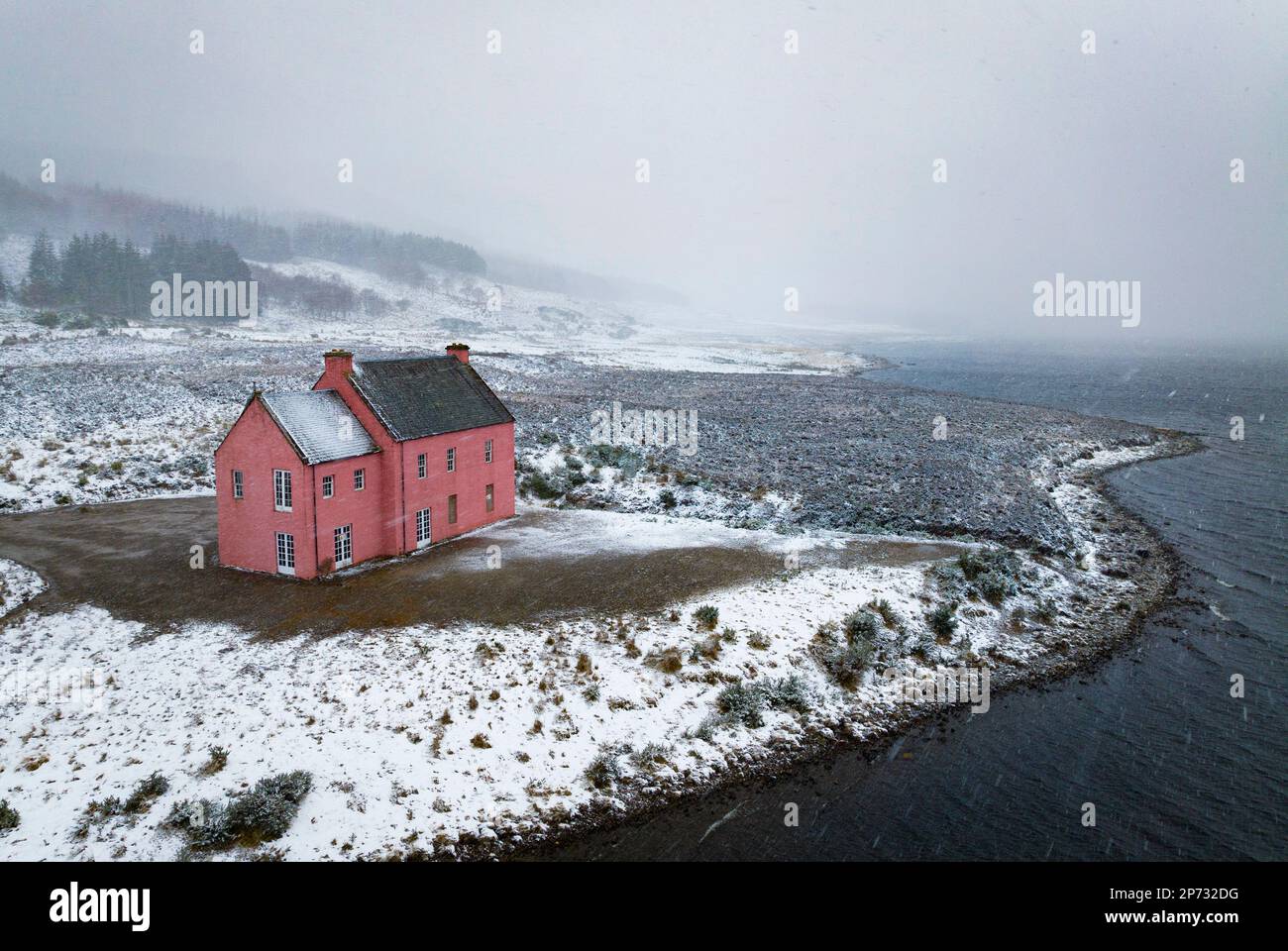 Vues aériennes de Culzie Lodge également connu sous le nom de Maison rose dans la neige sur les rives du Loch Glass à Pâques Ross, en Écosse Banque D'Images