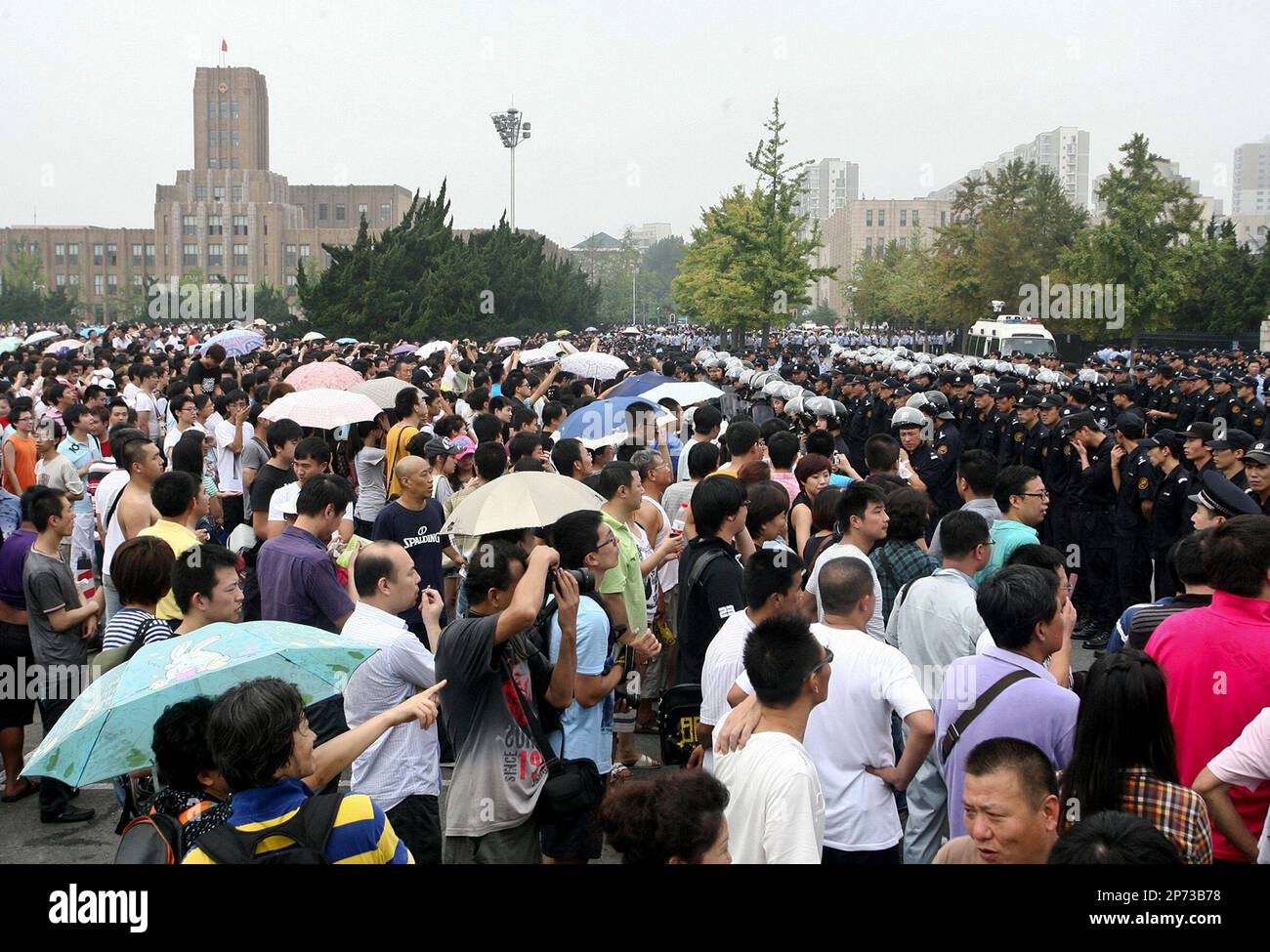 Chinese police officers face off with residents gathering at a square to demand relocation of a chemical plant after a toxic pollution scare in Dalian in northeast China's Liaoning province, Sunday, Aug. 14, 2011. Scuffles broke out Sunday between riot police and residents demanding that the chemical plant in northeastern China be moved after a tropical storm raised fears of a toxic spill, a state media report said. (AP Photo) CHINA OUT Banque D'Images