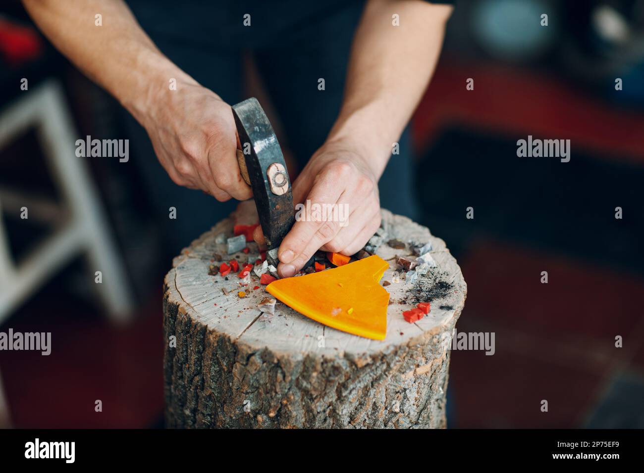 Artisan coupant le verre de smalt de rupture avec un marteau pour l'art de mosaïque dans l'atelier. Banque D'Images