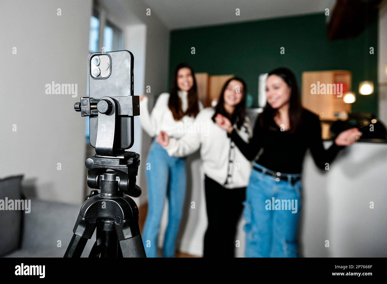 L'illustration montre un téléphone (smartphone) sur un trépied filmant 3  jeunes filles blanches dansant, à la maison, en mode selfie. Concept de  faire une vie avec des vidéos sur l'Internet en étant